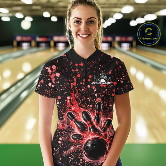 Female model wearing a black bowling quarter-zip shirt at the lane with red paint splatter music-themed bowling graphics.