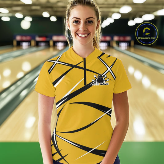 Front view of a female bowler wearing a yellow, black, and white bowling quarter zip shirt in a bowling lane
