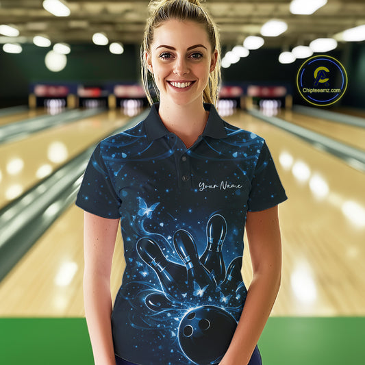 Female model wearing a black and blue bowling polo shirt at the lane with butterfly-accented bowling artwork.