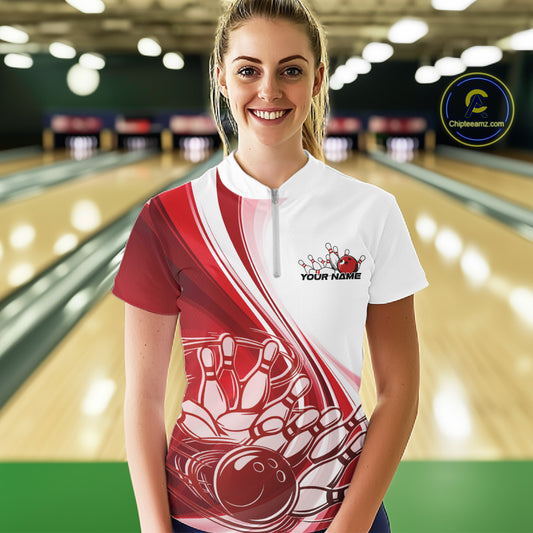 Female model at the bowling lane wearing a white and red bowling quarter zip featuring sweeping curve graphics and a bowling ball crashing into pins motif.