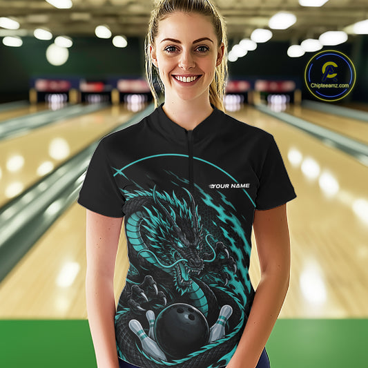 Front view of a happy female model in a bowling alley wearing a blue custom quarter-zip bowling shirt featuring an aggressive dragon with flames in a dynamic and energetic design.