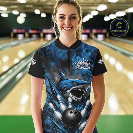 Person wearing a blue and black bowling shirt with a shark design in a bowling alley.
