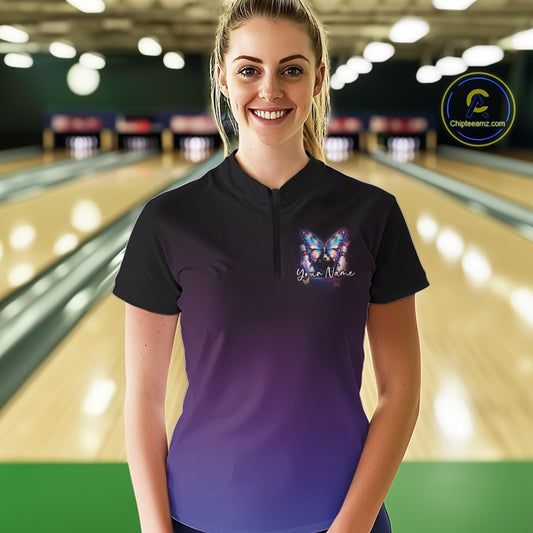 Female model wearing a colorful bowling quarter-zip shirt at a bowling lane with luminous butterflies, a bowling ball, and cosmic-themed artwork.