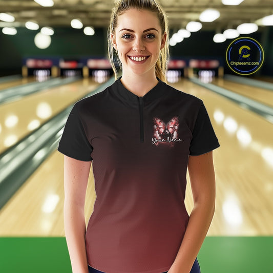 Female model at a bowling lane wearing a red bowling quarter-zip shirt with glowing butterfly artwork, a bowling ball, and cosmic-inspired graphics.