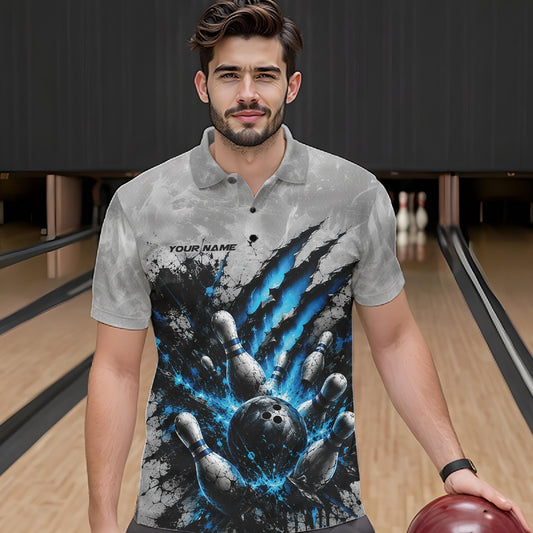 Front view of a male model wearing a gray bowling polo shirt showcasing a dramatic blue bowling ball striking pins graphic with claw-mark artwork in a bowling lane.