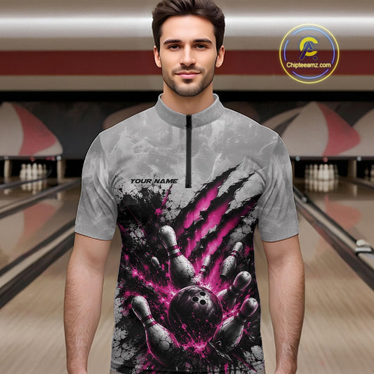 Front view of a male model wearing a gray bowling quarter zip shirt featuring a dramatic pink bowling ball and pins graphic with claw-mark artwork in a bowling lane.