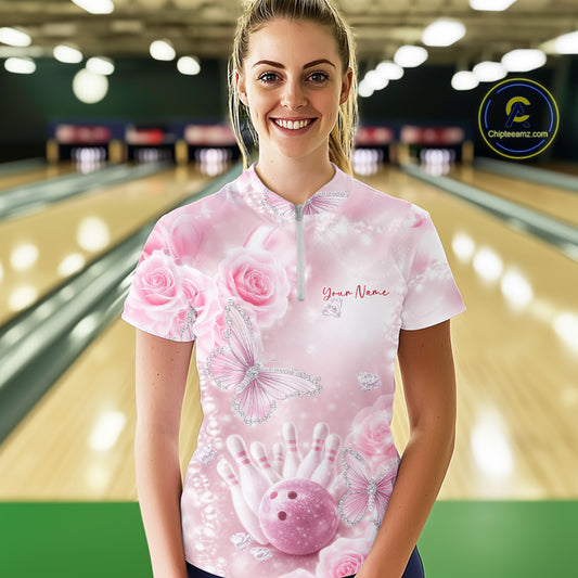 Female model shown from the front in a bowling center wearing a quarter-zip shirt featuring pink glitter butterflies, roses, bowling pins, and a bowling ball.