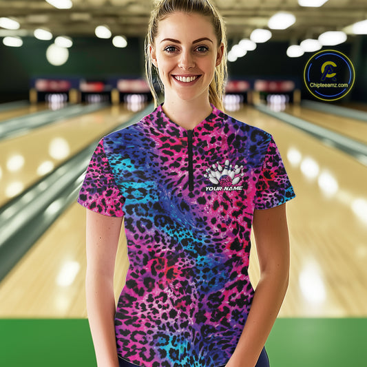 Smiling woman in a bowling alley wearing a purple, blue, and black leopard-print bowling quarter zip shirt with “Your Name” and a bowling pins graphic on the chest.