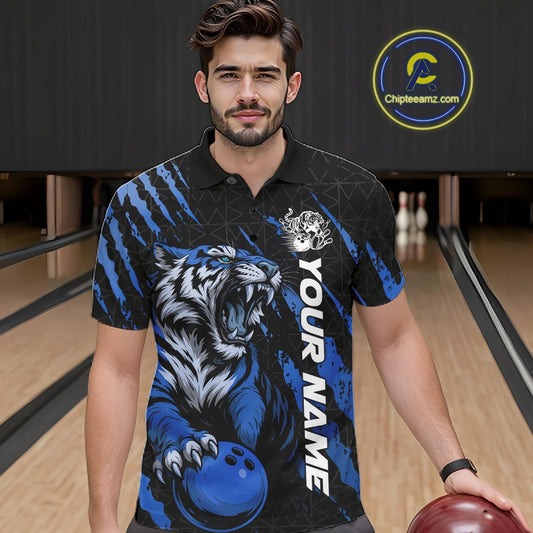 Front view of a male model wearing a black and mid blue bowling polo shirt at a bowling lane, showcasing a roaring tiger holding a mid blue bowling ball with matching claw-stripe artwork and a geometric background pattern.