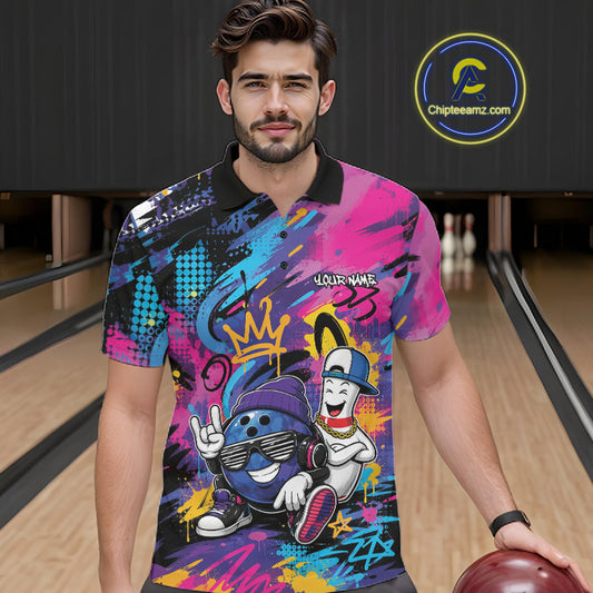 A man in a bowling alley wearing a vibrant, multicolor graphic polo shirt with funny cartoon bowling characters and graffiti-style patterns. He is holding a bowling ball, with bowling lanes visible in the background.