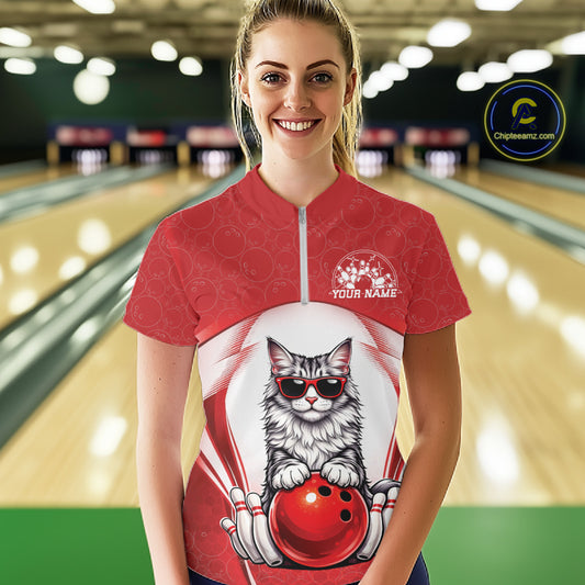 Female model at a bowling lane wearing a white and red bowling quarter-zip shirt with a Maine Coon cat in sunglasses leaning on a bowling ball.
