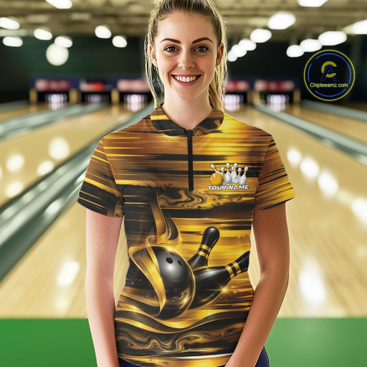 Front view of a female model inside a bowling center wearing a bowling quarter-zip shirt featuring glossy gold and black bowling ball and pins artwork.