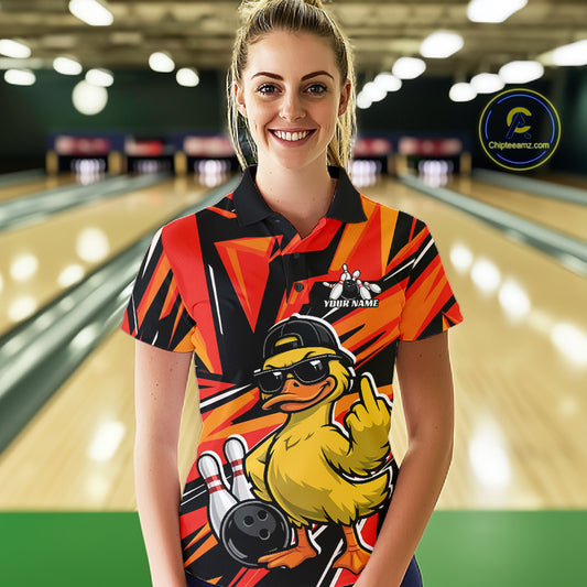 Female model at a bowling alley wearing a black and orange polo decorated with duck artwork, bowling pins, and geometric patterns.