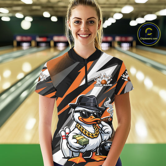 Female model in bowling lane wearing quarter-zip shirt featuring duck in sunglasses and fedora holding cash and cigar beside bowling ball and pins on black and orange design