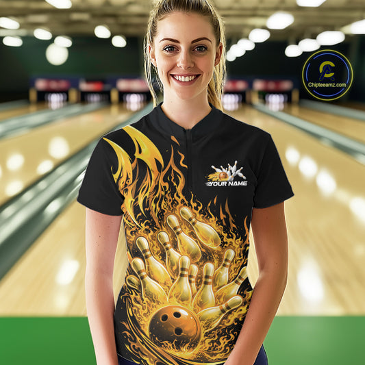Front view of female model at bowling lane wearing black and yellow quarter zip shirt with flaming bowling ball striking pins and dynamic fire themed artwork.