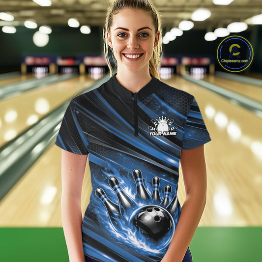 Female model in a bowling lane wearing black and blue quarter zip shirt, front view featuring fiery bowling ball hitting pins with bold abstract design