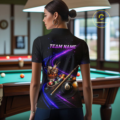 A woman stands in a billiards room wearing a black short-sleeve polo shirt with a vibrant purple and blue graphic print on the back featuring pool balls, a cue stick, and the text 'TEAM NAME'.
