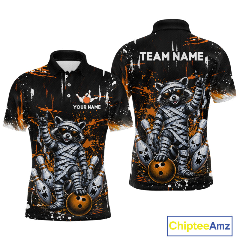 Custom short-sleeve polo shirt shown from the front and back, featuring a raccoon mummified in bandages holding bowling balls, with orange paint splatters on a black background. Includes customizable text areas.