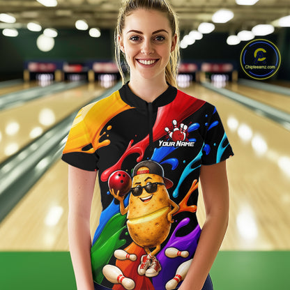 Person wearing a colorful bowling shirt with a cartoon potato design in a bowling alley.