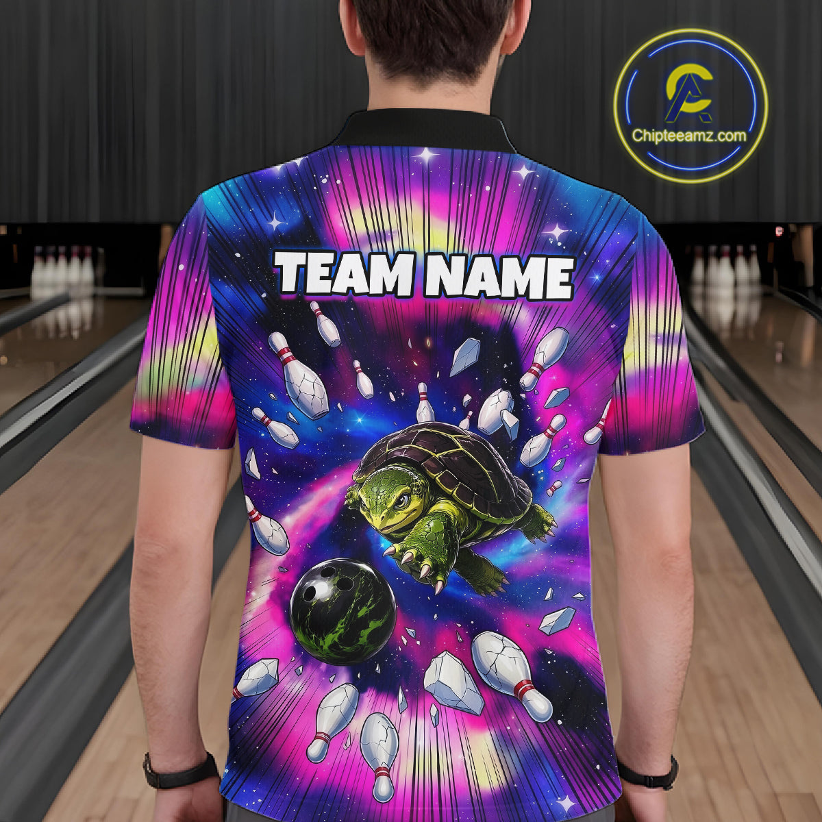Person wearing a colorful bowling shirt with a turtle design and 'TEAM NAME' text in a bowling alley.
