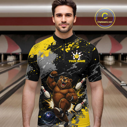 A man wearing a custom bowling-themed short-sleeve shirt with a black and yellow paint splatter design, a cartoon bear bowling, and 'YOUR NAME' text on the chest. The background shows blurred bowling lanes