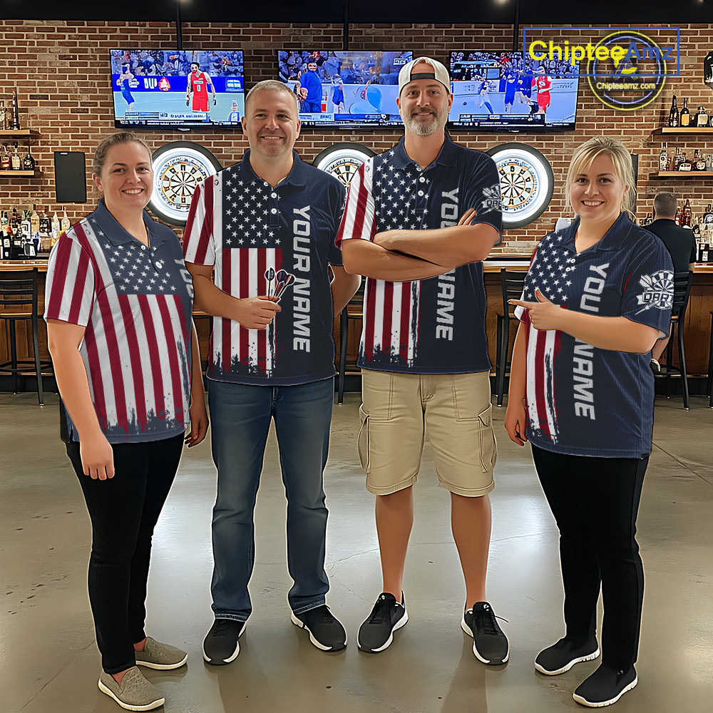 Four people standing together in a bar setting, wearing matching navy blue polo shirts with a distressed American flag print and vertical 'YOUR NAME' text. The shirts feature red and white stripes and white stars.