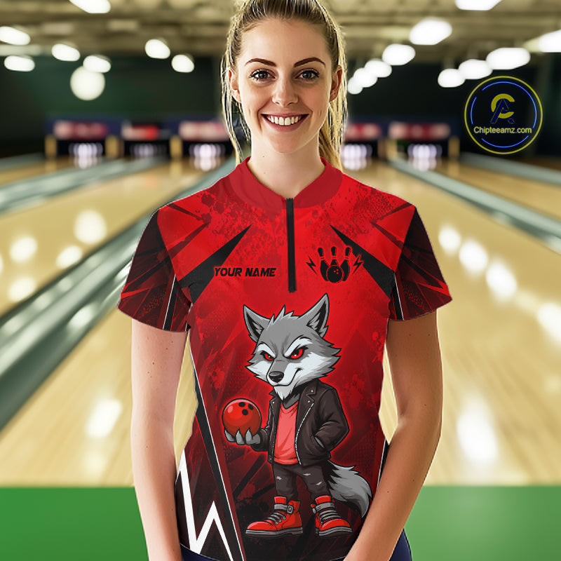 Woman wearing a red and black bowling quarter zip shirt featuring a gray wolf mascot holding a red bowling ball, with custom player name text.