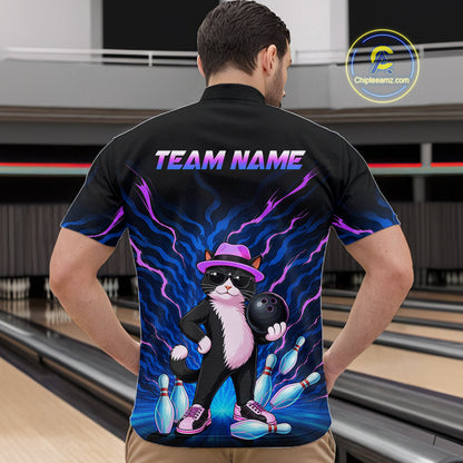 A man viewed from behind wearing a black short-sleeve bowling shirt with a colorful graphic of a cat holding a bowling ball, set against a bowling alley background. The shirt features 'TEAM NAME' printed on the back.