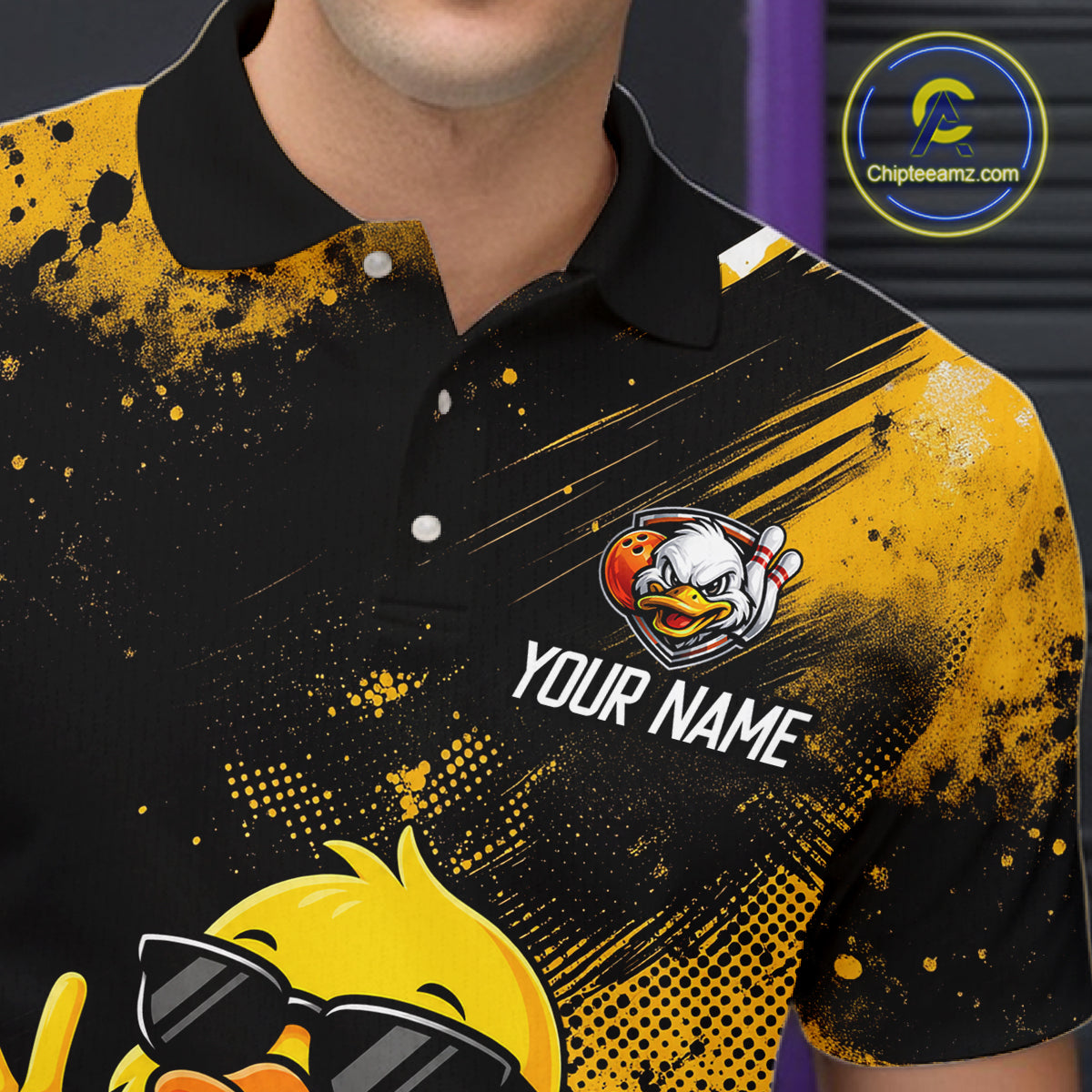 A close-up of a person wearing a black and yellow polo shirt with a custom cartoon duck graphic, the text 'YOUR NAME', and a circular 'Chipearnz.com' logo on the upper chest.
