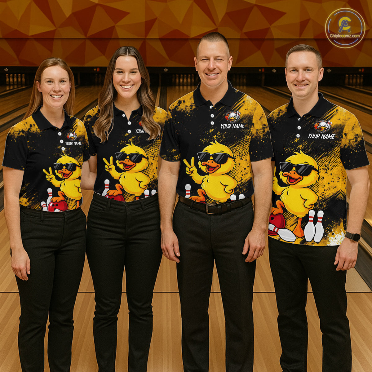 Four people standing together in a bowling alley wearing matching black and yellow bowling shirts with a cartoon duck graphic, black pants, and bowling pins visible in the background.