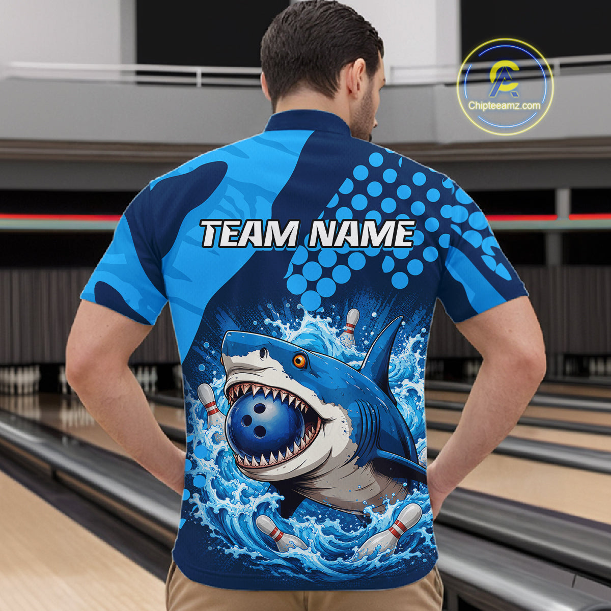 Man wearing a blue and black bowling shirt with a shark graphic and 'TEAM NAME' text on a bowling alley background.