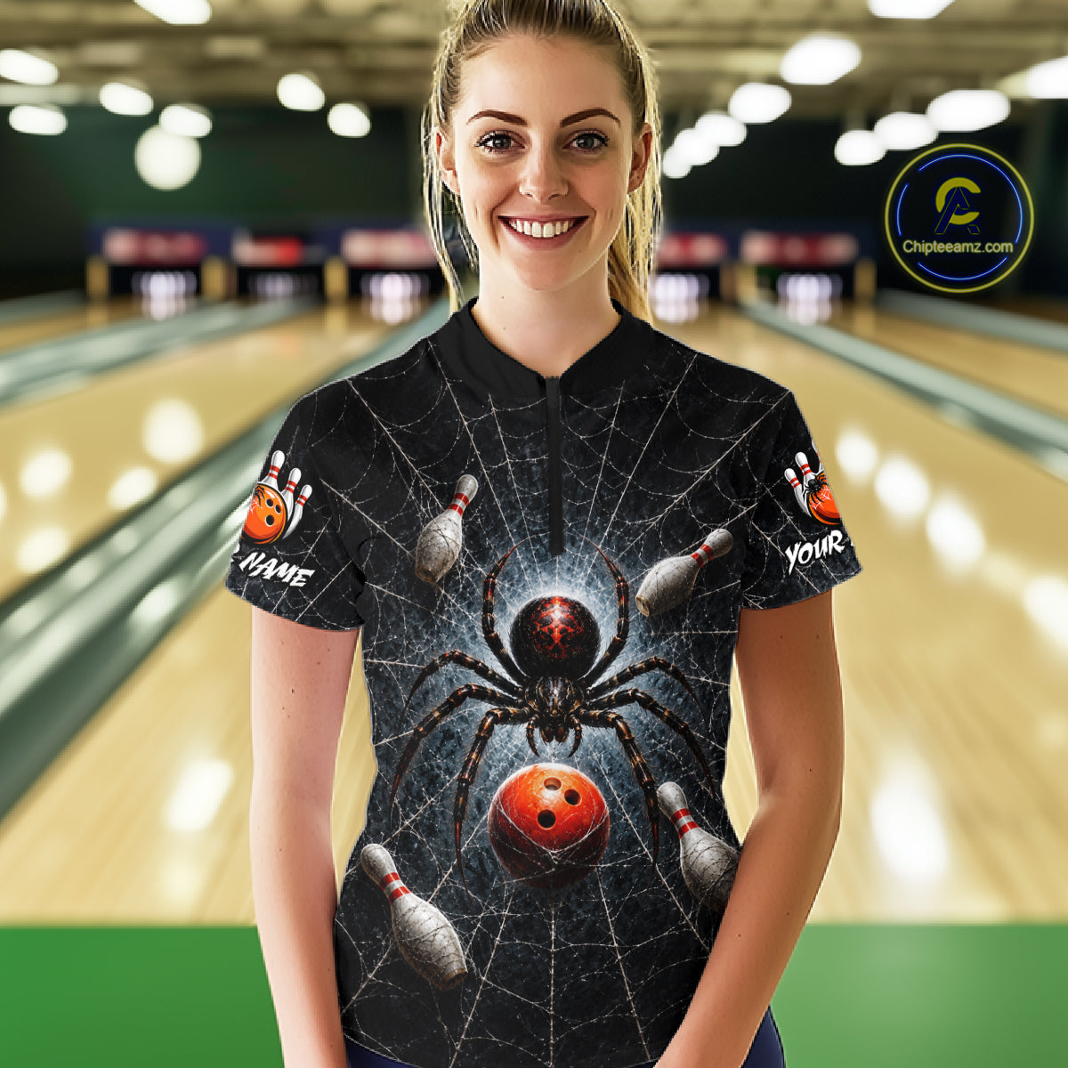 A woman standing in a bowling alley wearing a black short-sleeve bowling-themed t-shirt with a large spider and bowling ball graphic on the front, with bowling pins and lanes visible in the background.
