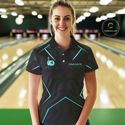 Woman wearing a black bowling shirt with teal accents in a bowling alley.