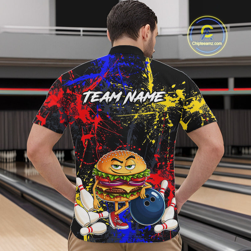 A man viewed from behind wearing a black short-sleeve bowling shirt with a colorful paint-splatter design and a cartoon burger holding a bowling ball. The shirt has 'TEAM NAME' printed across the upper back.