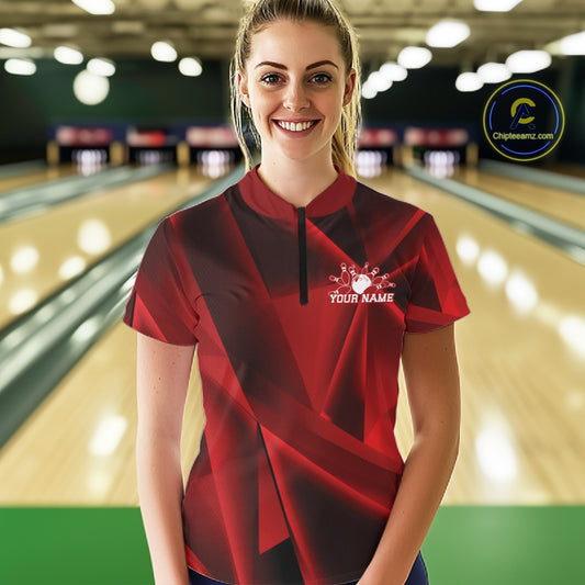 Woman wearing a red and black bowling shirt with a logo and text in a bowling alley.