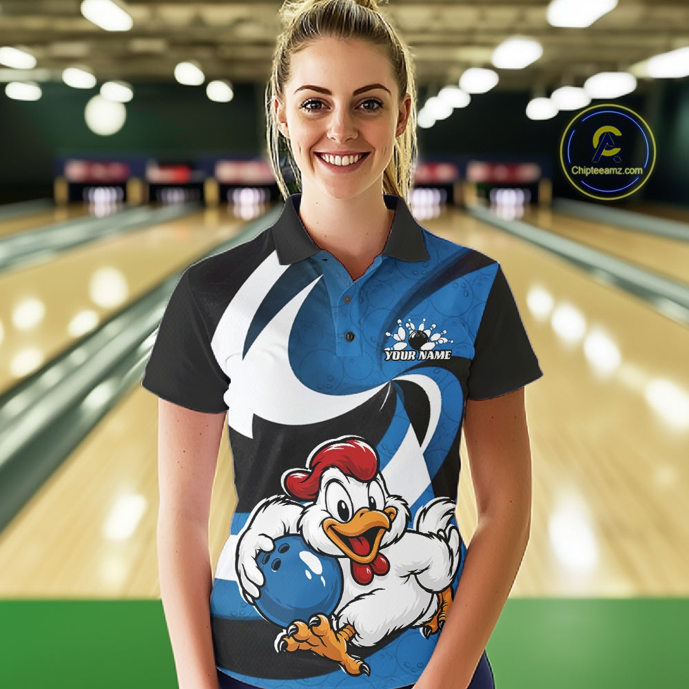 A woman stands in a bowling alley wearing a custom printed polo shirt. The shirt features a black and blue design with a large cartoon rooster holding a blue bowling ball, and the text 'YOUR NAME' on the chest.
