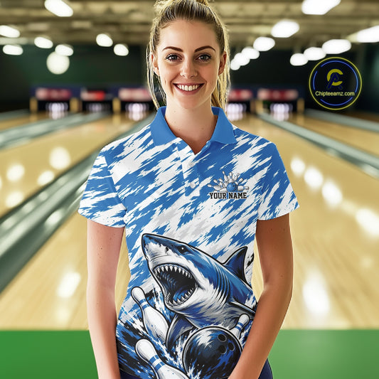 Woman wearing a blue and white bowling shirt with a shark design in a bowling alley.