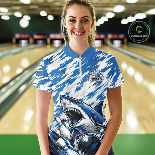 Person wearing a blue and white bowling shirt with shark design in a bowling alley.