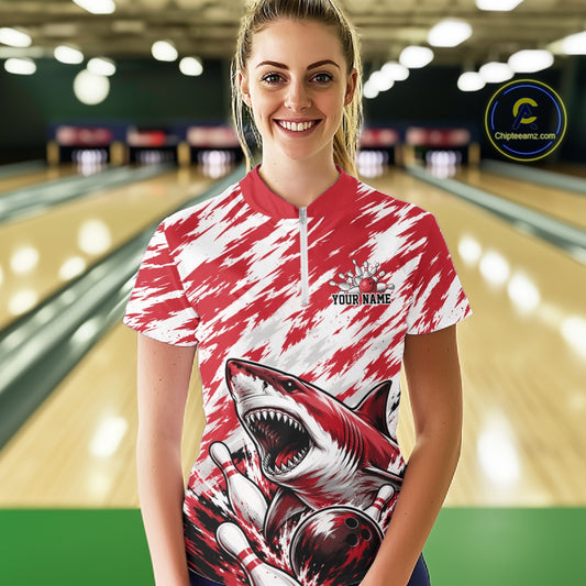 Person wearing a red and white bowling shirt with a shark design in a bowling alley.
