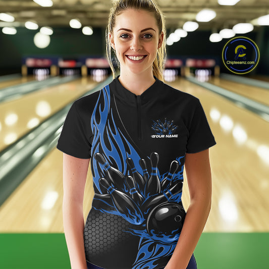 Female model front view in bowling alley wearing black quarter zip shirt with blue flame bowling ball hitting pins illustration