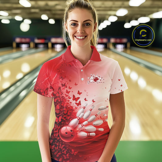Female model wearing a white and red bowling polo shirt featuring butterfly artwork and bowling-themed graphics at the bowling lane.