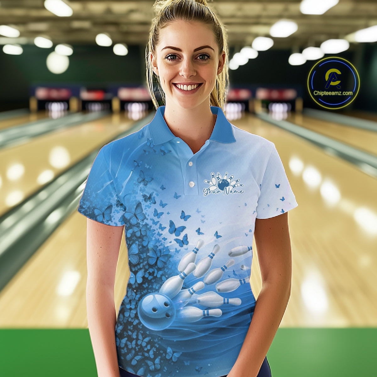 Front view of a female model in a white and blue bowling polo shirt featuring butterfly accents and bowling graphics at the bowling lane.