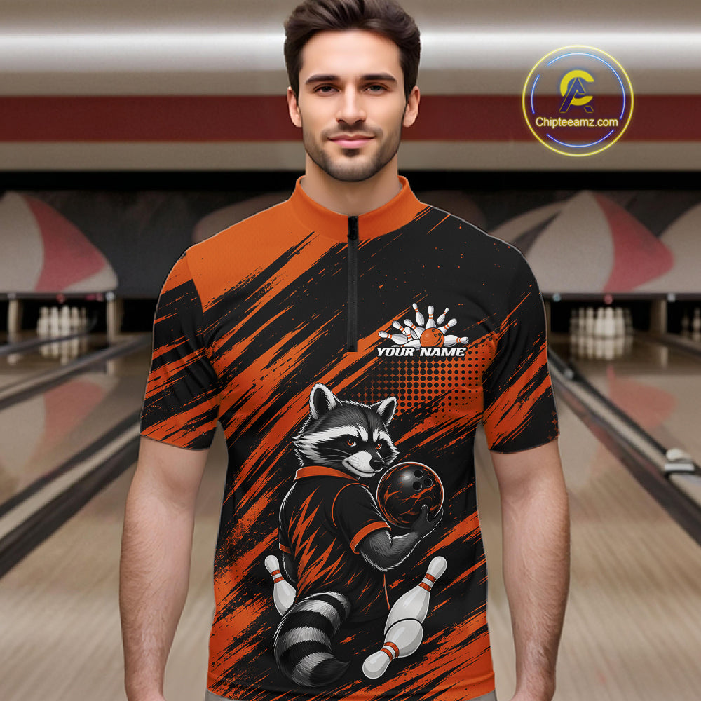 A man wearing a short-sleeve quarter-zip bowling jersey with a raccoon graphic and orange/black brushstroke pattern, set against a bowling alley background. 
