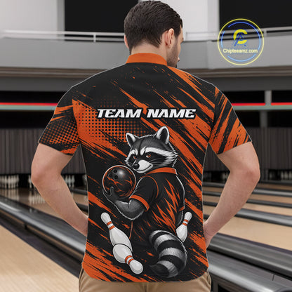 A man viewed from behind wearing a short-sleeve bowling quarter zip shirt with a raccoon graphic and the text 'TEAM NAME' on the back. The shirt has a black and orange brush-stroke pattern with a raccoon holding a bowling ball, set in a bowling alley environment.