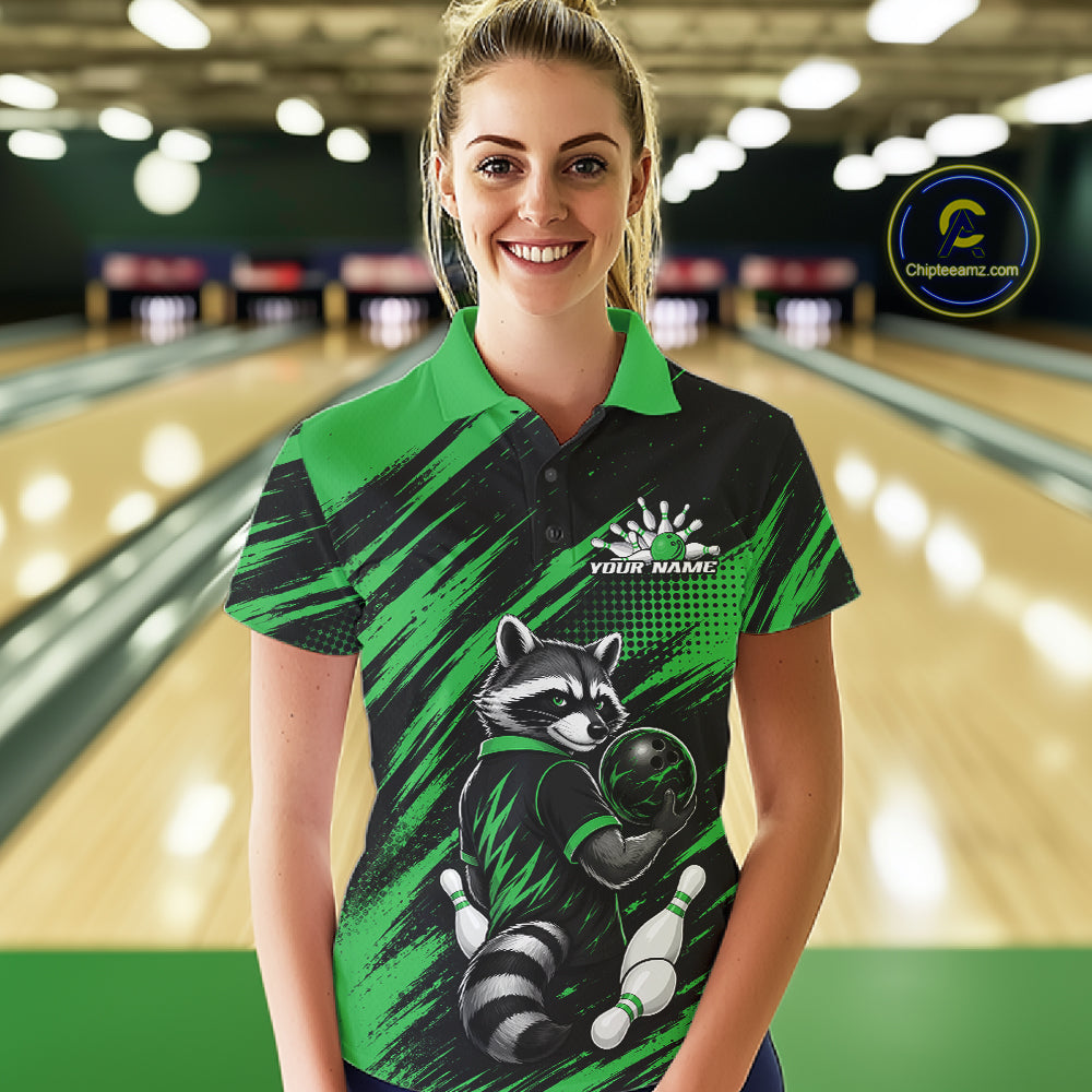 A woman stands in a bowling alley wearing a custom short-sleeve polo shirt with a raccoon bowling graphic. The shirt features a black and green brush-stroke pattern with a white raccoon holding a bowling ball