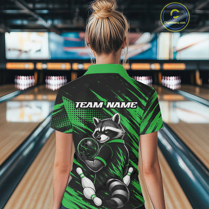 A woman viewed from behind wearing a short-sleeve bowling shirt with a raccoon graphic and 'TEAM NAME' text, standing in a bowling alley. The shirt is black and bright green with a raccoon illustration and bowling pins.