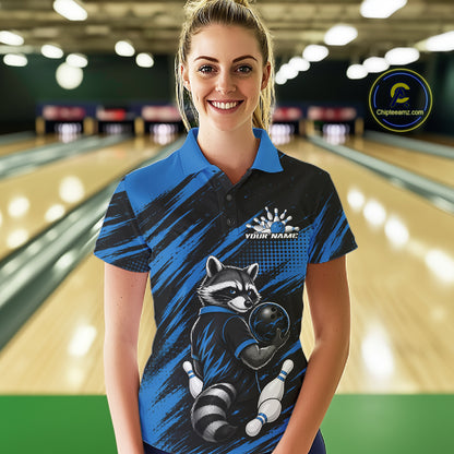 A woman stands in a bowling alley wearing a custom blue and black short-sleeve bowling quarter zip shirt with a raccoon graphic and 'YOUR NAME' printed on the chest. 