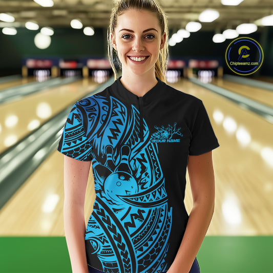 Female model wearing a black and blue bowling quarter-zip shirt at the bowling lane with Polynesian-inspired bowling motifs.
