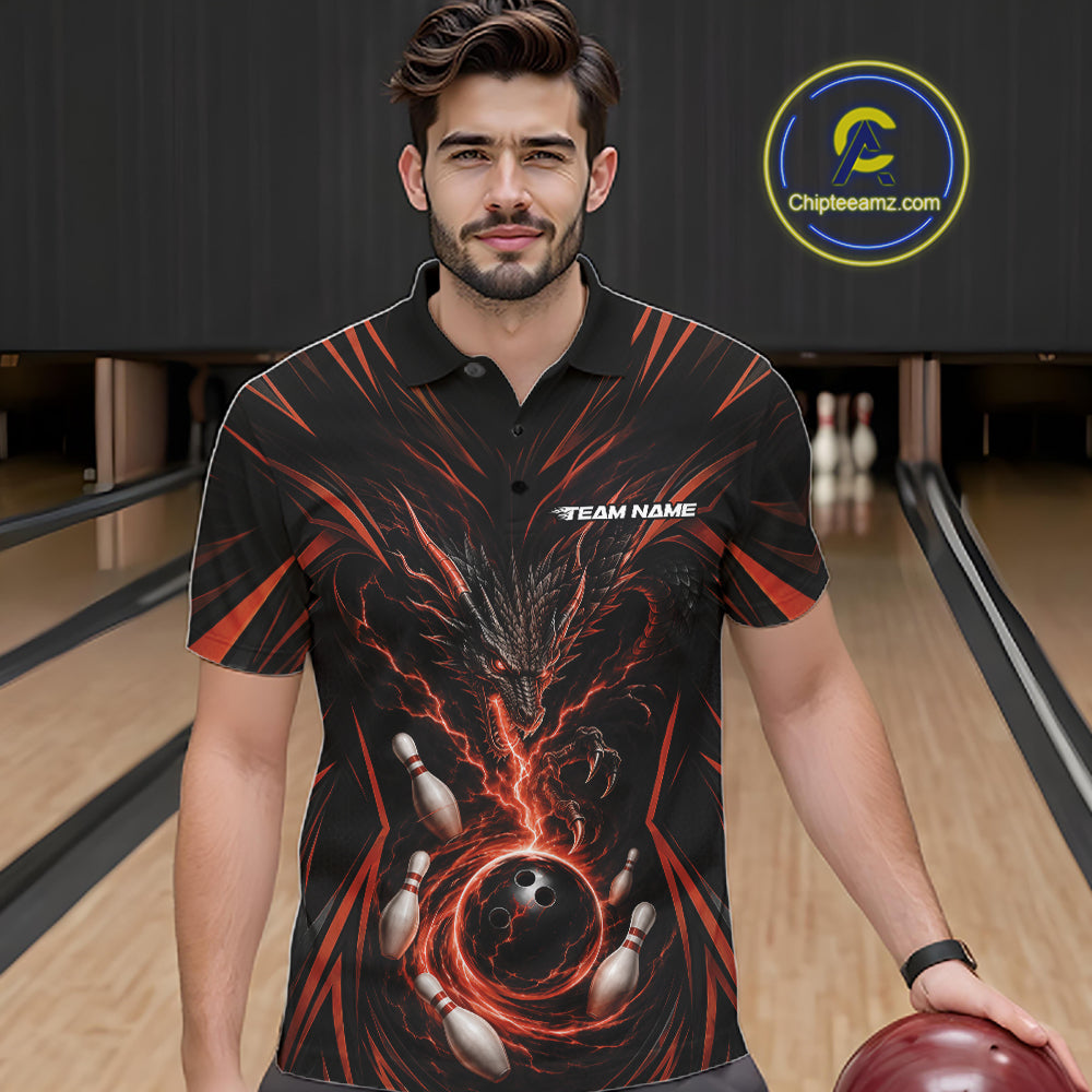 A man wearing a black short-sleeve bowling-themed polo shirt with a red and orange dragon graphic and bowling pins and ball design, standing in a bowling alley holding a bowling ball.