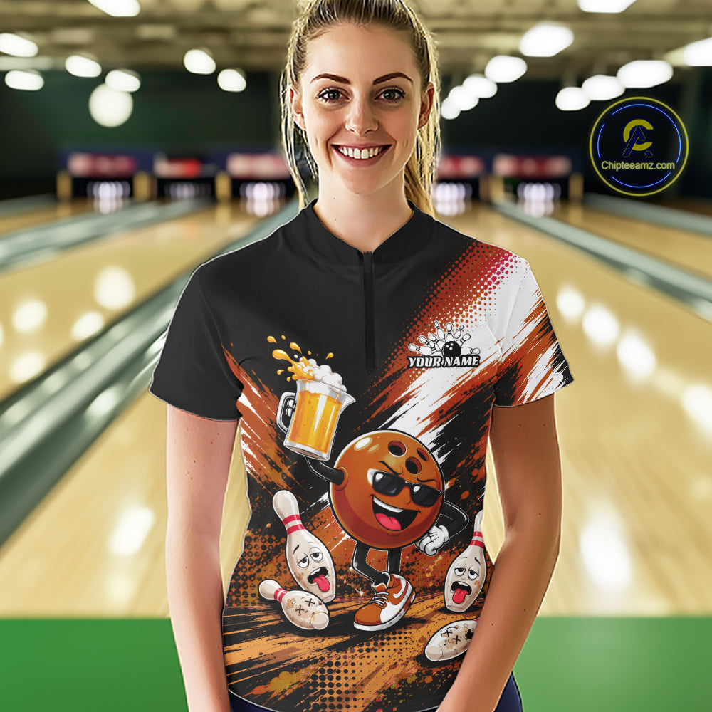 A woman stands in a bowling alley wearing a short-sleeve black quarter zip-style shirt with a colorful bowling-themed graphic print. The shirt features a cartoon bowling ball character, bowling pins, bowling pins falling, a beer mug, and customizable text placeholders.